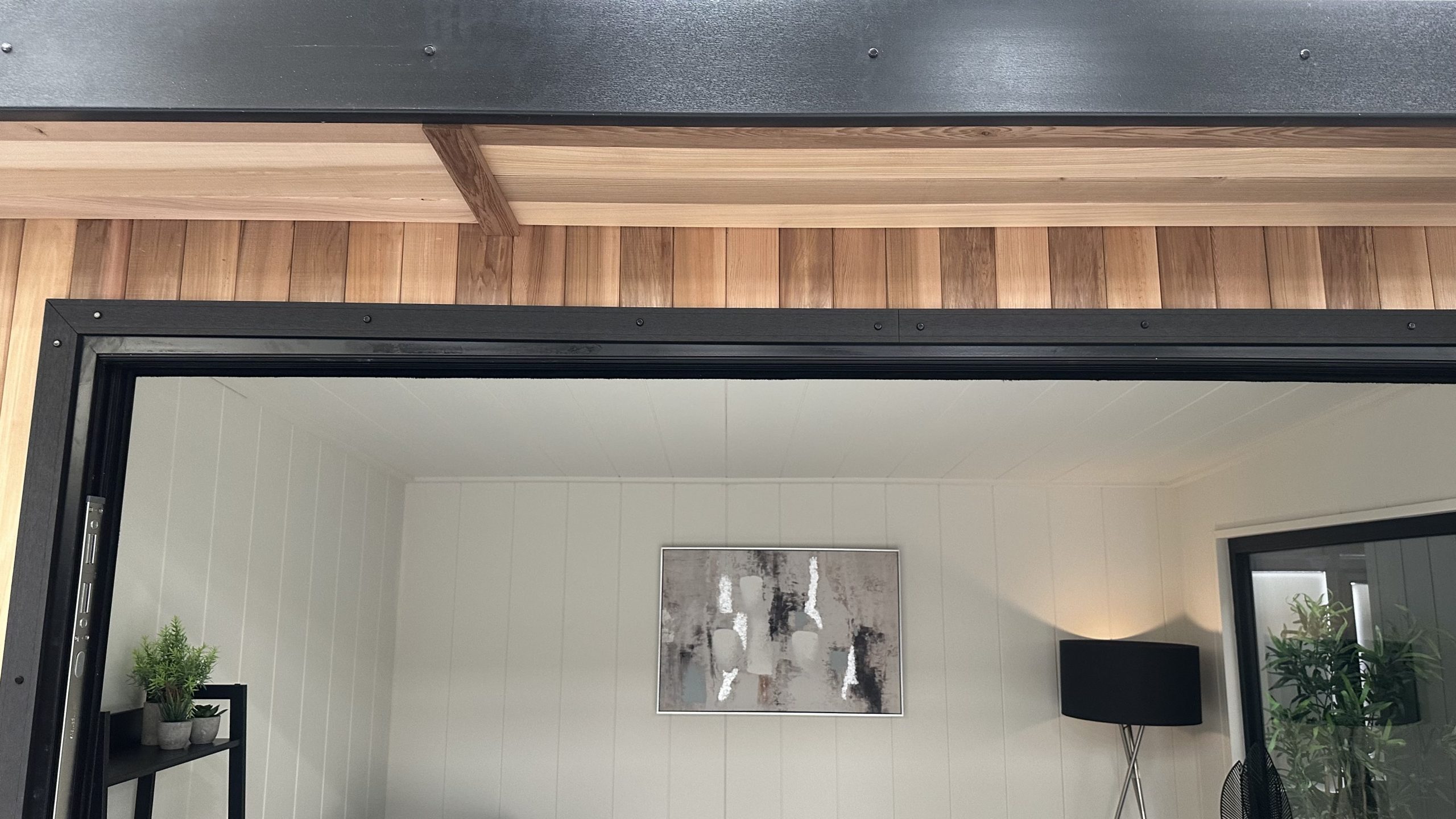 Cedar cladding and dark door framing around a finished garden room interior.